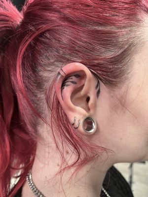 Elegant hand-poked ear tattoo by Marketa featuring intricate dotwork design.