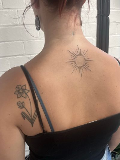 Experience the artistry of Marketa.handpoke with this beautifully detailed sun tattoo done in fine line hand poke style.