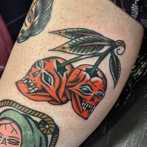 Get inked with a bold traditional tattoo featuring a skull and cherry motif by talented artist Benji Charnock. Classic yet unique! 