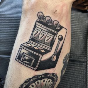 Get lucky with this traditional slot machine tattoo, expertly done by the talented artist Benji Charnock.