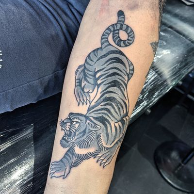 Get a fierce and timeless traditional tiger tattoo by the talented artist Benji Charnock. Roar with style!