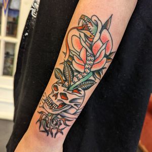 Get an edgy and bold traditional tattoo of a snake wrapped around a skull by artist Benji Charnock. Perfect for those who love classic tattoo motifs.