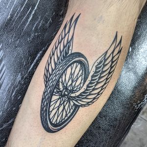 Experience the freedom and movement with this illustrative tattoo of a wheel and wings, expertly designed by Benji Charnock.