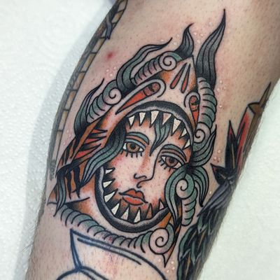 Check out this awesome traditional tattoo of a shark and woman by Benji Charnock. Bold lines and vibrant colors make this piece truly standout!