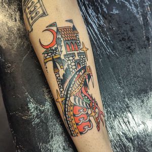 Get inked with this captivating traditional tattoo featuring a snake and castle, expertly done by artist Benji Charnock.