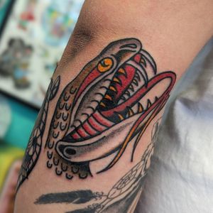 Experience the timeless artistry of traditional tattooing with this striking snake design by talented artist Benji Charnock.