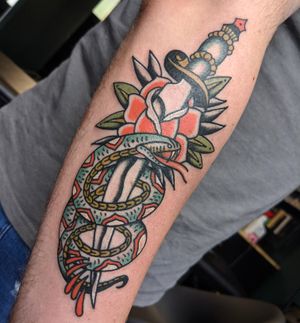 Get inked with this classic traditional tattoo design featuring a striking snake and dagger motif, expertly executed by renowned artist Benji Charnock.