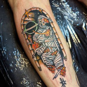 Get mesmerized by Benji Charnock's unique fusion of a mummy design with a dark, mysterious black hole motif in this traditional style tattoo.