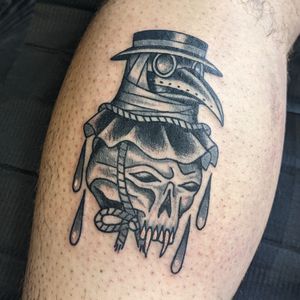 Experience the haunting beauty of Benji Charnock's unique traditional style tattoo featuring a skull and plague doctor motif. Perfect blend of dark and intricate design.