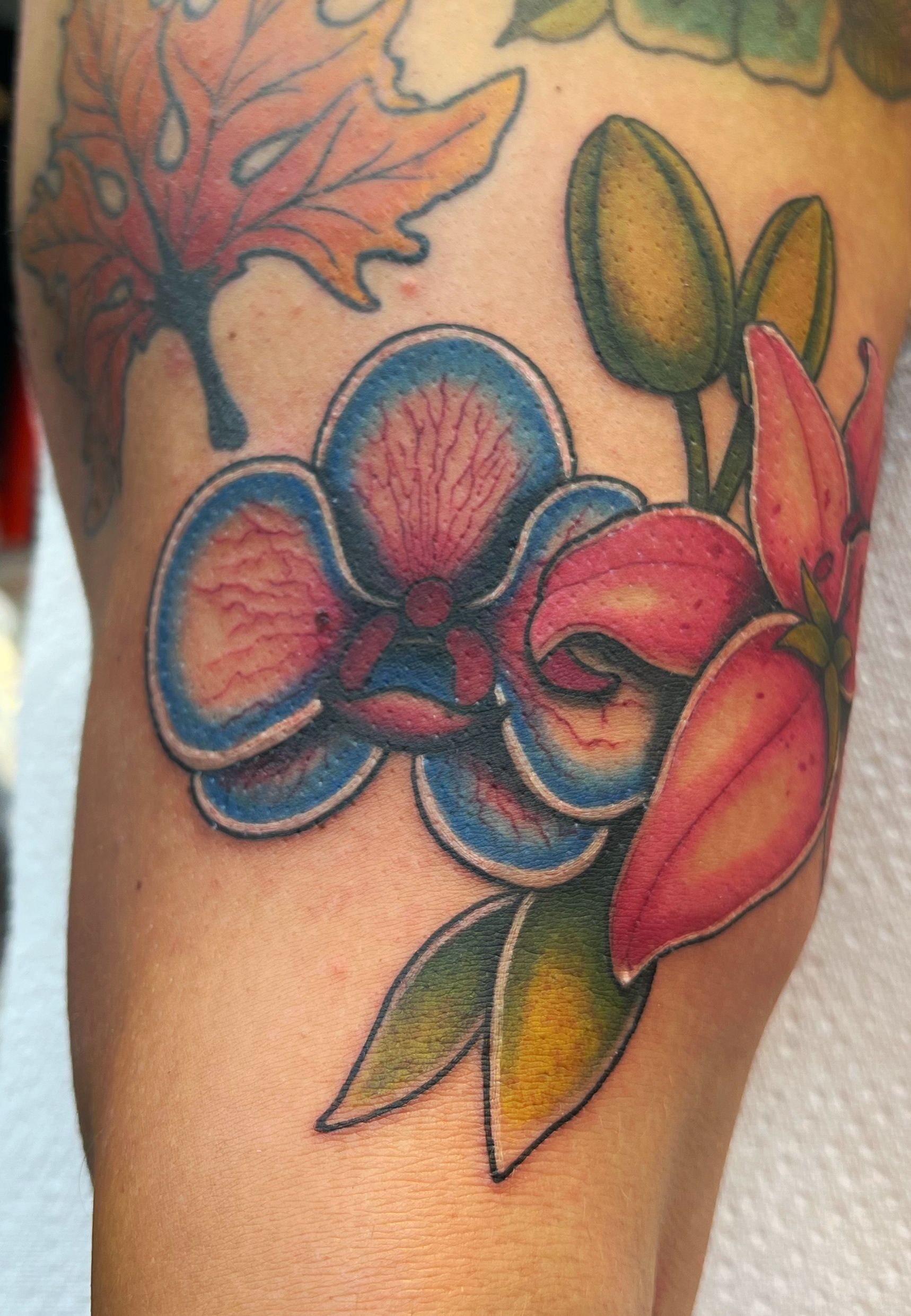 Orchids tattooed on the wrist in fine line style.