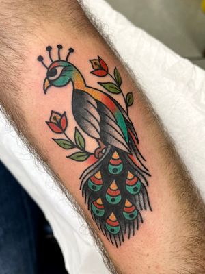 Get vibrant and timeless peacock design with a touch of tradition by tattoo artist Clara Colibri. Perfect for those seeking a classic and eye-catching piece.