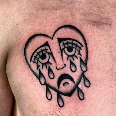 Embrace the emotion with Clara Colibri's traditional tattoo featuring a sad face inside a heart motif.