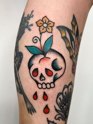Experience the bold contrast of delicate flowers and fierce skulls in this stunning traditional tattoo by Clara Colibri.