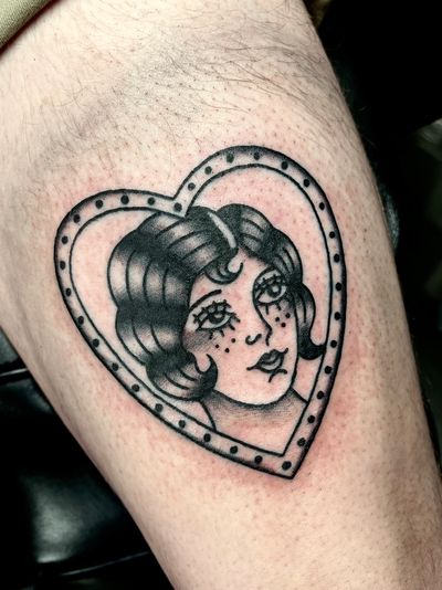 A stunning traditional tattoo featuring a beautiful lady enclosed in an ornate frame, expertly done by Clara Colibri.