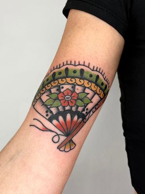 Experience the timeless beauty of a traditional fan tattoo expertly crafted by renowned artist Clara Colibri.