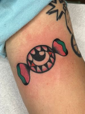 Experience the sweet and mystical vibe with Clara Colibri's traditional tattoo featuring a candy and eye motif.