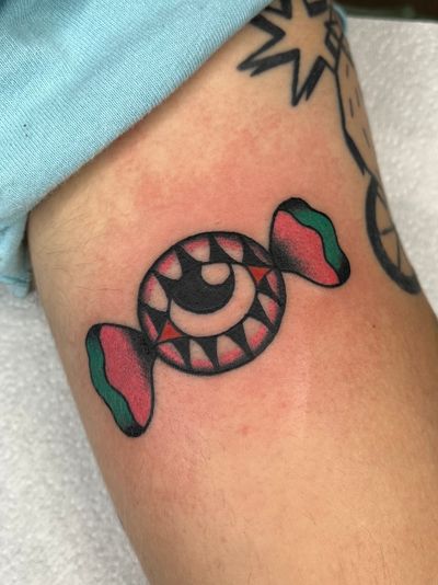 Experience the sweet and mystical vibe with Clara Colibri's traditional tattoo featuring a candy and eye motif.