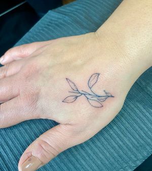 Experience the intricate beauty of a fine line hand poke tattoo featuring a elegant vine and branch motif by Charlotte Pokes.