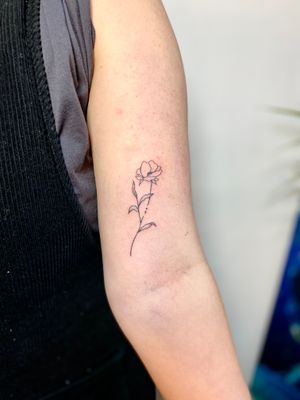Elegant and delicate hand-poked tattoo featuring a beautiful flower motif by Charlotte Pokes.
