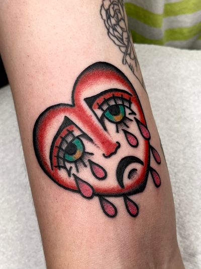 Express your emotions with this traditional heart tattoo featuring a sad motif, expertly done by Clara Colibri.