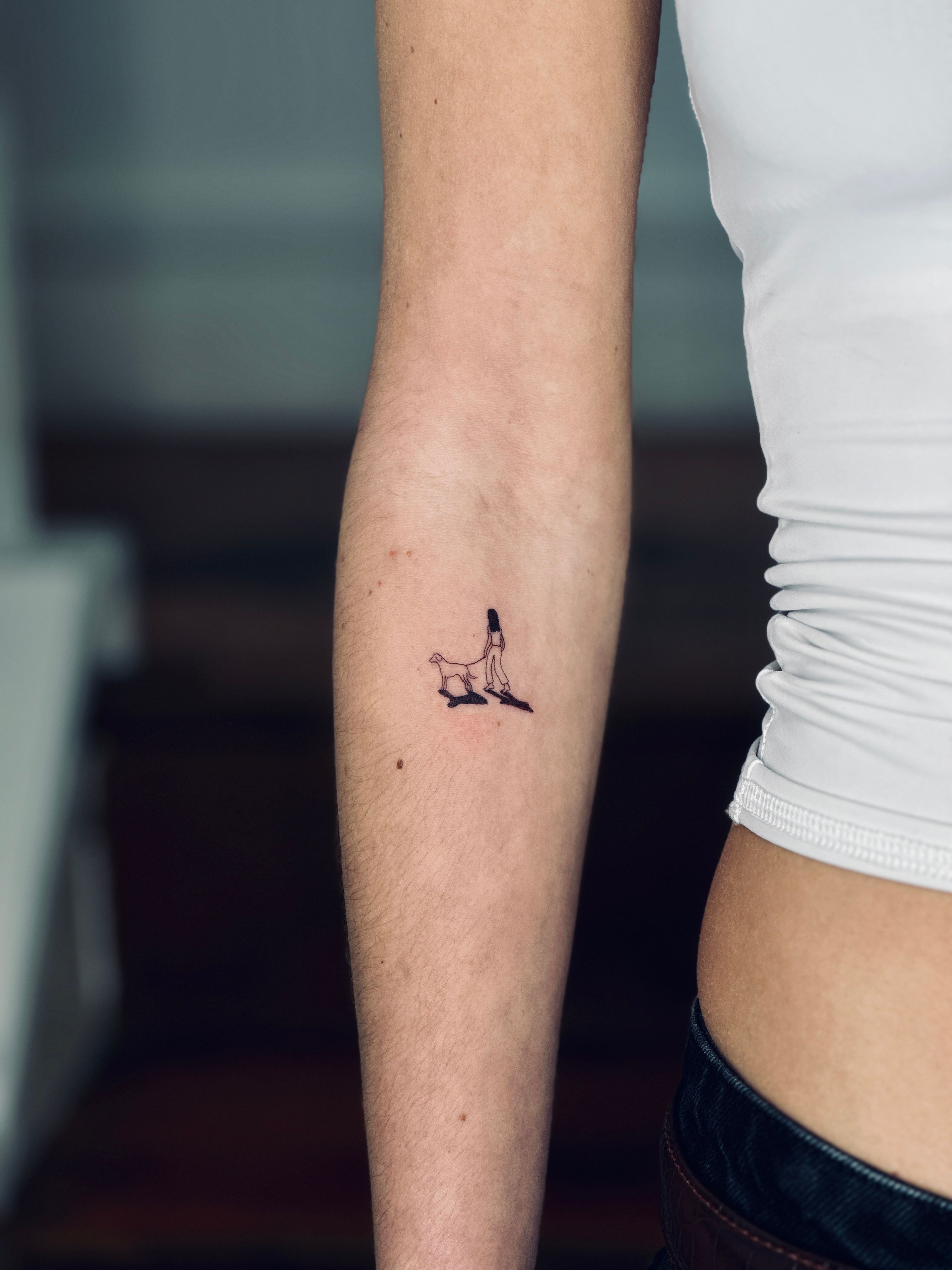 Minimalist rabbit portrait tattoo on the upper arm.