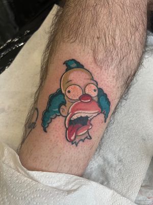 Get a fun and colorful illustrative tattoo of Krusty the Clown from The Simpsons by talented artist Ben Prescott.