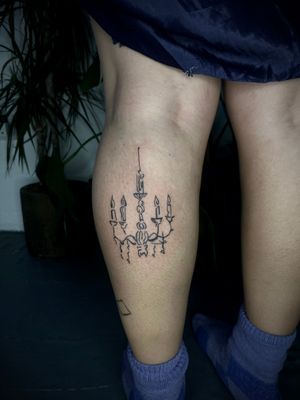 Experience the unique artistry of Emily Bonnet with this beautifully detailed candle and chandelier tattoo design.
