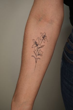 Fine line floral tattoo showcasing a beautiful lily flower, created by artist Lucas Scardua.