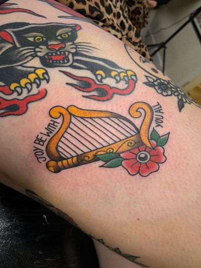 Capture the beauty of music with this traditional tattoo featuring a harp instrument design by Laurel. Perfect for music lovers!