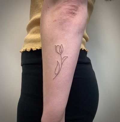 Elegant fine line tulip tattoo by Chloe Hartland, showcasing intricate single line design
