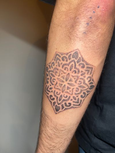 Experience the beauty of hand-poked dotwork with this stunning mandala tattoo by skilled artist Andrew Maher.