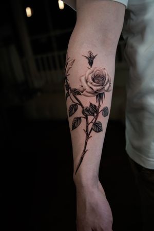 Admire the delicate beauty of this black and gray rose tattoo, expertly done by Delphin Musquet. Perfect for lovers of realism.