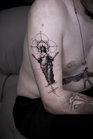Delphin Musquet beautifully blends black and gray tones to create a stunning micro-realism tattoo of a statue in a geometric design. A true masterpiece.