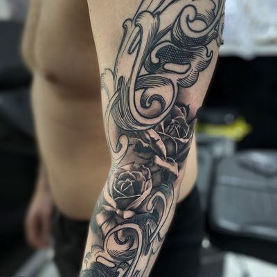Stunning black and gray illustrative tattoo by Gaston Gromnicki featuring a detailed rose and intricate filigree designs.