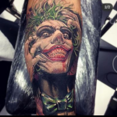 Get a stunning realism tattoo of the iconic Joker character from comics, expertly done by Gaston Gromnicki.