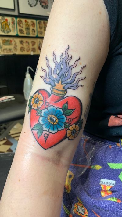 Embrace the sacred with this stunning traditional tattoo featuring a sacred heart motif, expertly crafted by the talented artist Laurel.