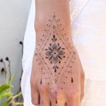 Elegant hand-poked dotwork tattoo of a flower design by Indigo Forever Tattoos, featuring intricate ornamental details.