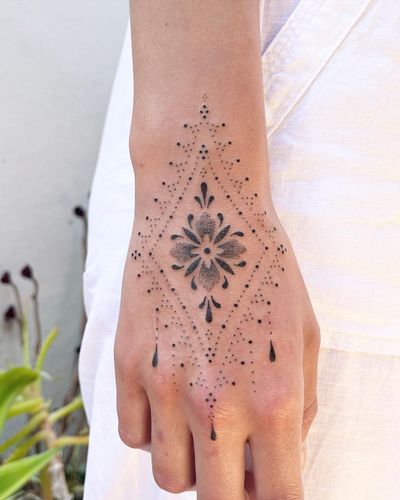 Elegant hand-poked dotwork tattoo of a flower design by Indigo Forever Tattoos, featuring intricate ornamental details.
