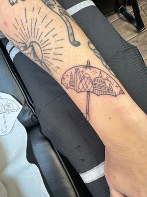 Illustrative tattoo featuring a stylish umbrella design with London skyline elements, by Kiky Flore.
