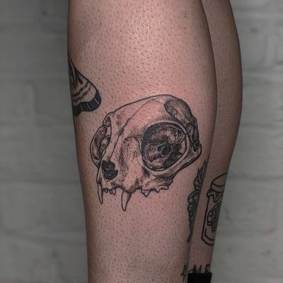 Get a unique dotwork tattoo of a cat and skull by the talented artists at Alien Ink. Express your love for felines and the darker side of life in one stunning design.