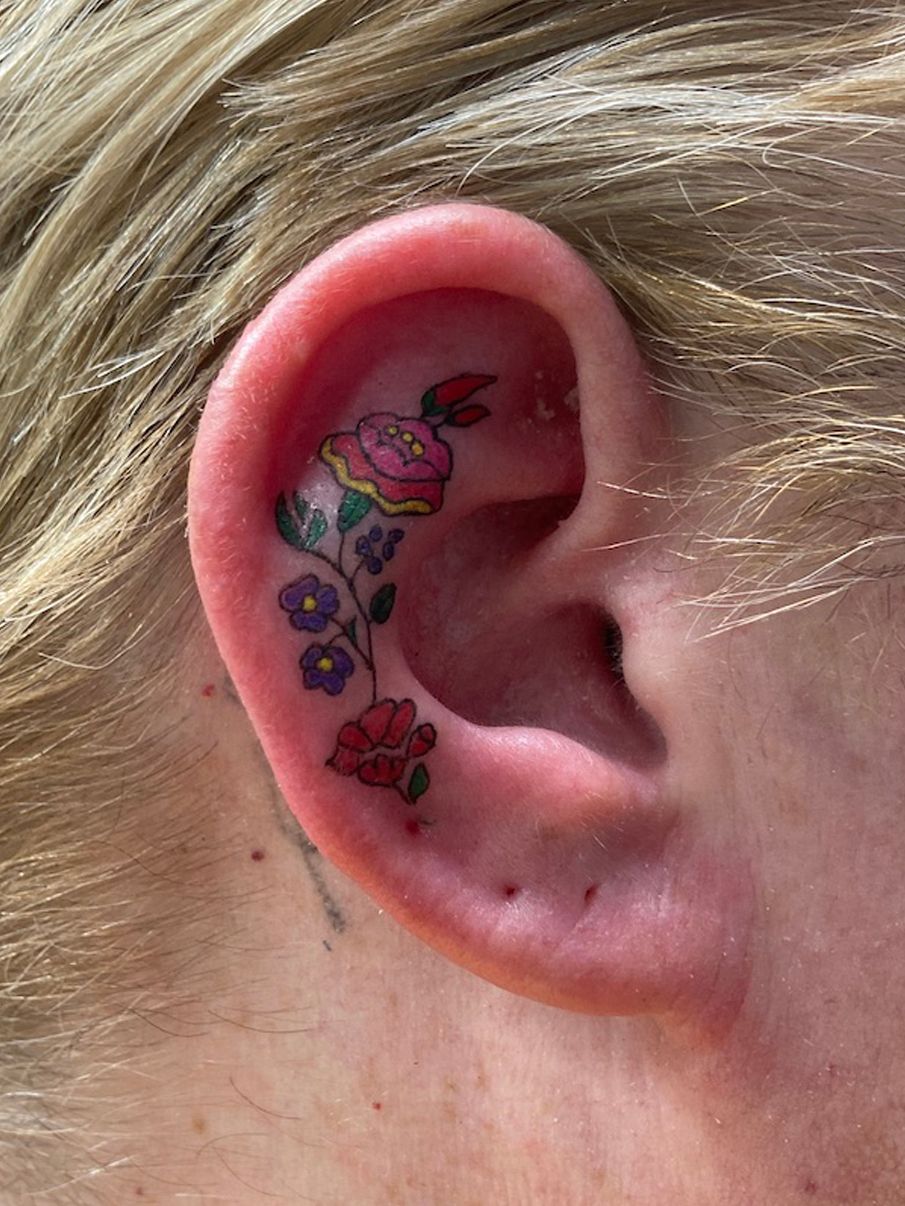 Colorful flower tattoo on the left ear - Tattoogrid.net