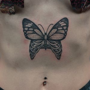 Unique hand-poked dotwork butterfly tattoo on ribcage by Alien Ink, combining illustrative elements for a stunning design.