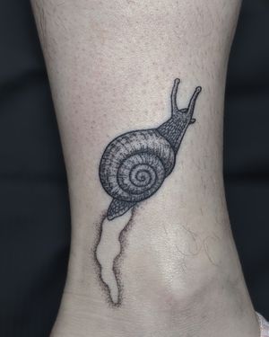 Experience the slow and steady beauty of a hand-poked, blackwork snail tattoo by the talented artists at Alien Ink.