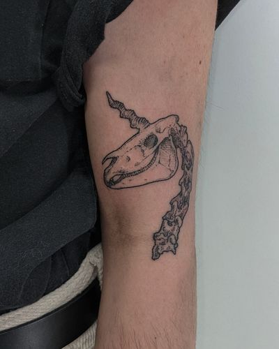 Unique hand-poked illustrative tattoo featuring a mystical unicorn and a haunting skull, expertly done by Alien Ink.