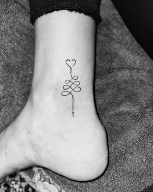 This fine line tattoo beautifully combines a heart and an unalome symbol, creating a delicate and intricate design by artist Larisa Andreea Boboc.