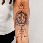 Stunning black and gray fine line tattoo of a fierce lion holding a geometric sword, by Gabriele Edu. Perfect balance of realism and geometry.