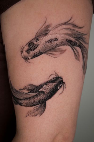Experience the beauty and elegance of a black-and-gray, realistic koi fish tattoo by tattoo artist Alexander Rufio.