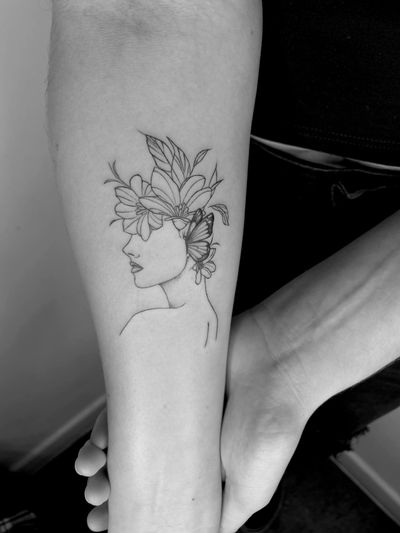 Capture the beauty of nature with this exquisite fine line tattoo featuring a woman surrounded by flowers, expertly created by Ruth Hall.