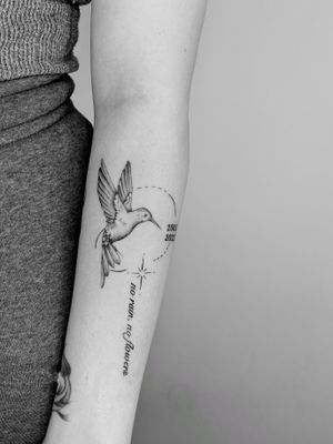 This illustrative tattoo by Ruth Hall features a fine line geometric design with small lettering, showcasing a beautiful hummingbird motif.