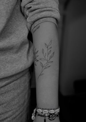 Experience the delicate beauty of a fine line branch tattoo expertly crafted by renowned artist Ruth Hall.